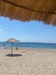Sunny beach with straw umbrella