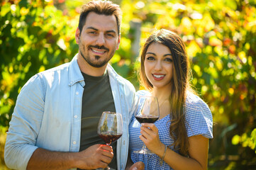 Winemakers couple holding glasses of red wine in vineyard