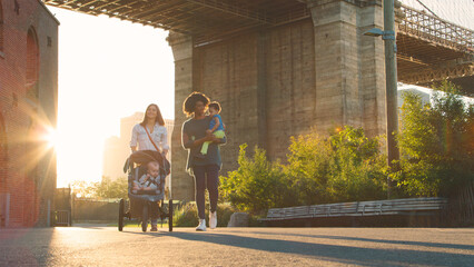 Obraz premium Family Day Out In New York City With Two Mums Walking By Brooklyn Bridge With Children 