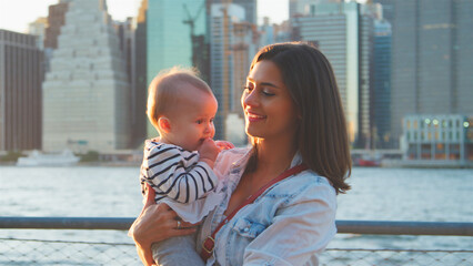 Family Day In New York With Mother Holding Baby Daughter Standing In Front Of Manhattan Skyline 