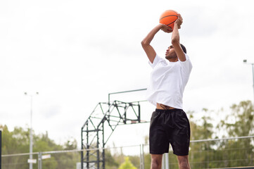 Fototapeta premium Male basketball player throwing the ball to the basket