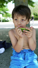 Boy enjoying a slice of watermelon, showcasing the joy and delight of eating a refreshing summer fruit in a bright and sunny outdoor setting