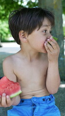 Fototapeta premium Boy enthusiastically eating a slice of watermelon, enjoying the refreshing fruit in a sunny outdoor setting, capturing the joy of summer snacks