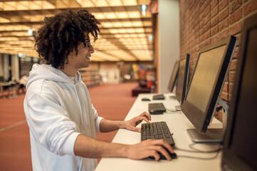 Curly-haired male engaged in online education preparing for project using computer