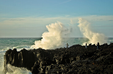 Ocean waves over people and rocks