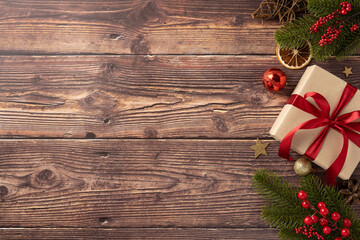 A beautifully wrapped Christmas gift with a red ribbon sits on a wooden table alongside festive...