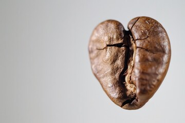 Naklejka premium Heart-shaped coffee bean on a white background. Love for coffee and minimalistic design concept.