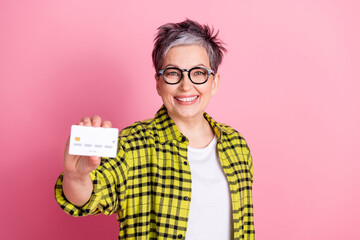 Photo of nice aged woman hold debit card checkered shirt isolated on pink color background