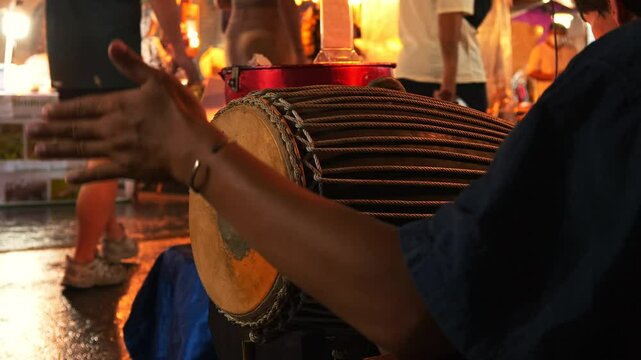 Street musician playing a tabla - a traditional Indian drum, with fingers and palms, at Night Market, Chiang Mai, Thailand