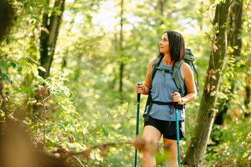 A woman finds joy and peace during a rejuvenating hike in a vibrant forest, fully embracing natures...