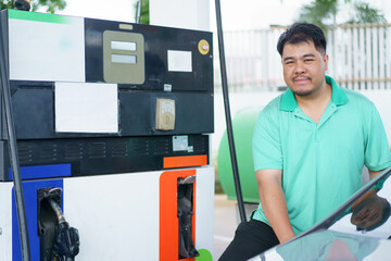 Asian man is refuels his car a gas.