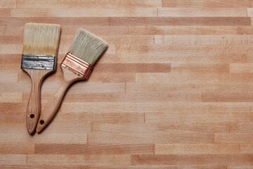 Two paintbrushes on a wooden surface with ample copy space