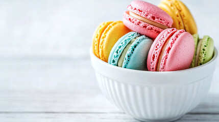 Macaroons in bowl on white wooden table close-up, copy space for text