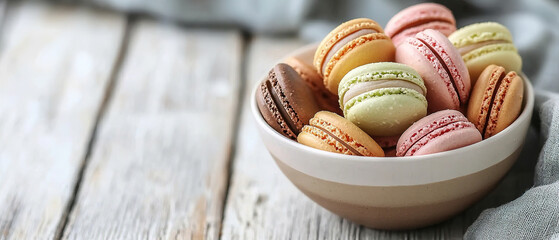 Macaroons in bowl on white wooden table close-up, copy space for text
