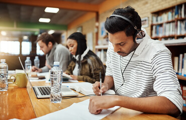 Man, writing and notes in library for education, studying and headphones for music. Student, study...