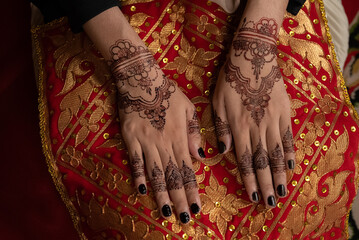 The bride's hands decorated with henna. There are many different names for henna tattoos around the world, such as mehndi, inai, hina, camphire, and hena