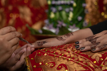 The process of painting henna on the bride's hands. There are many different names for henna tattoo...