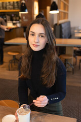 Beautiful young woman in coffee shop looking ahead