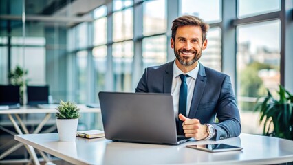 Fototapeta premium Confident businessman sitting at modern desk, smiling while displaying laptop screen to showcase digital content, gesturing professionally with hands, in a bright office setting.
