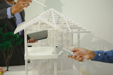 Engineers are discussing house construction plans, reviewing blueprints, assessing materials, and...