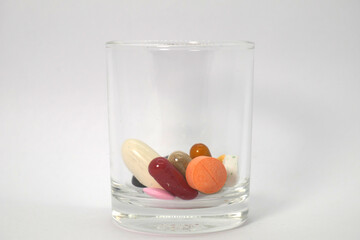 close up of colorful medicine tablets, capsules, and pills  in the glass on the white background isolated
