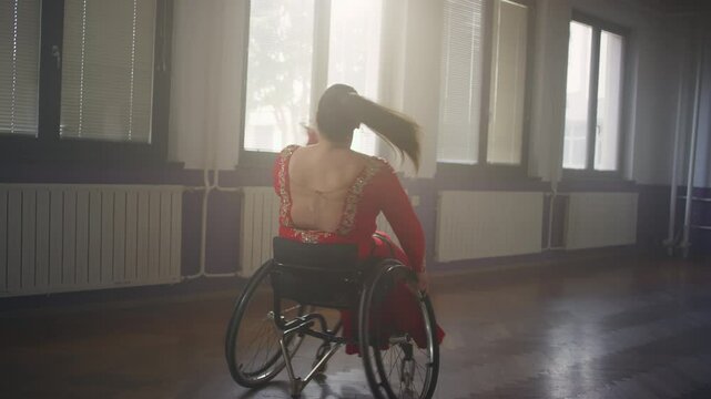 Woman with a disability, a skilled wheelchair dancer enjoying performing her choreography at a ballroom, handheld shot. Para dance sport concept.
