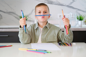Boy draws with colored pencils. Learning and education concept. Children's activity at home.
