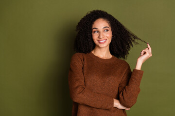 Portrait of pretty young woman hold hair look empty space wear sweater isolated on khaki color background