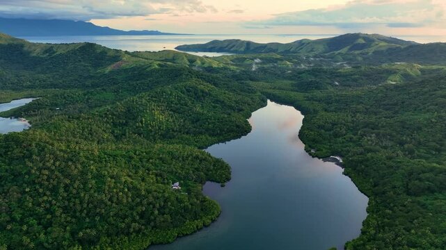 Aerial view of lush tropical rain forest with a winding river and majestic mountains, Fiji.