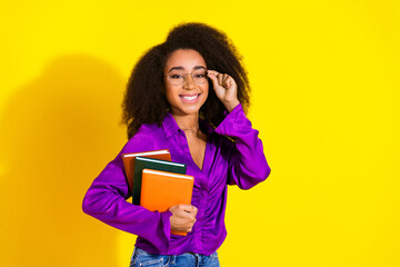 Photo portrait of pretty young girl hold books reader wear trendy violet outfit isolated on yellow color background