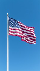 Waving American flag under clear blue sky during bright daylight hours