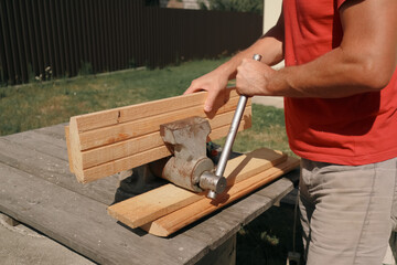 A carpenter planes a piece of wood using an electric plane. Carpenter is planing a wooden plank