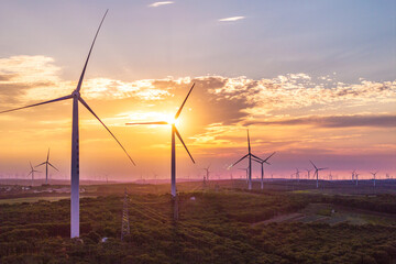 view of wind power turbine in field at sunset