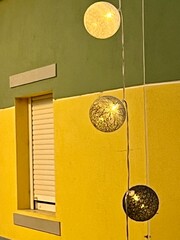 Decorative hanging balls in front of bright building and window