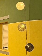 Decorative hanging balls in front of bright building and window