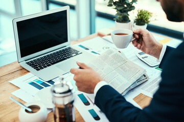 Business man, newspaper and coffee with reading, stock market and info for work in office. Laptop, statistics and investment news in paper with financial advisor and research in finance section