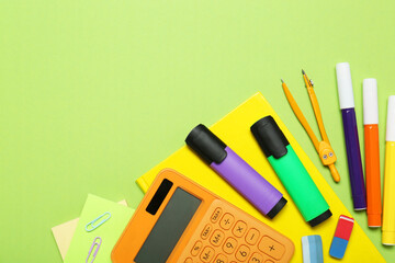 Different school supplies and calculator on light green background, flat lay. Space for text