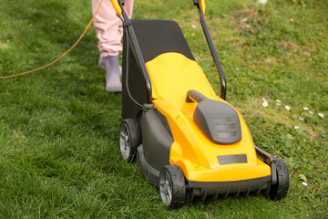 Yellow lawn mower on the spring green grass in the yard	