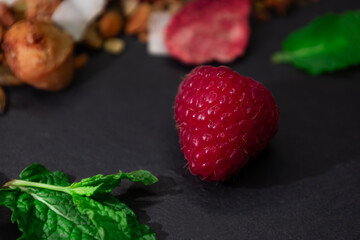 Honey, crispy, golden handmade granola with nuts, coconut, banana, seeds, bright strawberries and raspberries. A sprig and leaves of mint add freshness. Gray background, copy space, text place, banner