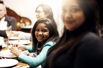 Portrait, happy and child in dining room for Christmas, lunch and religious holiday at home with family. December, smile or girl kid in apartment for social gathering, traditional celebration or love