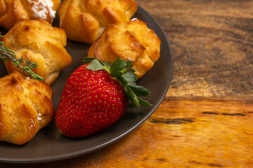 Fresh strawberry and profiteroles on ceramic plate.