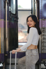 A woman is standing in front of a train with a suitcase