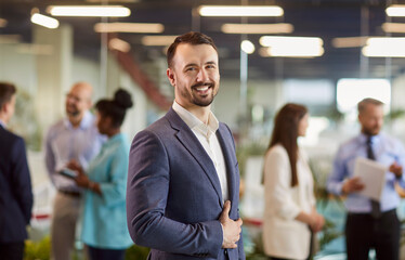 Confident young businessman looking at the camera against the backdrop of a crowd of people. Happy businesswoman in the lobby. Concept business success, confident man, expert people