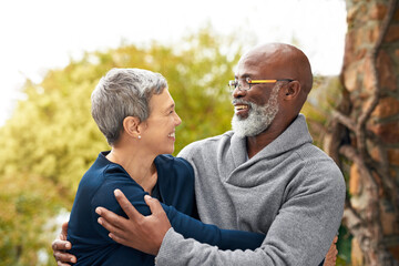 Interracial senior couple, smile and love in park, garden or nature for hug or care together. Happy man, woman and partner for retirement, relax and support for marriage and vacation for pensioner