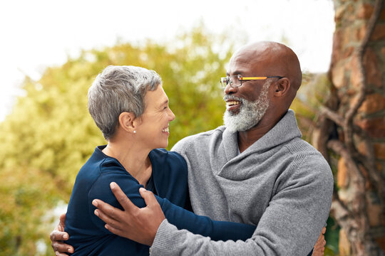 Interracial senior couple, smile and love in park, garden or nature for hug or care together. Happy man, woman and partner for retirement, relax and support for marriage and vacation for pensioner