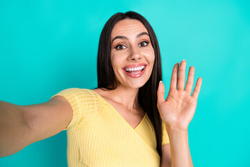 Portrait of pretty young woman selfie arm wave hi wear top isolated on turquoise color background © deagreez