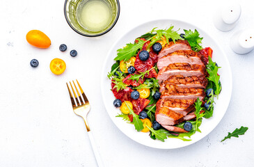 Fresh salad with grilled duck and sicilian orange, blueberry, chard, lettuce and arugula on white background, top view
