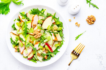Old fashioned salad with chicken, red and green apples, raw celery, lettuce and walnuts, white background, top view