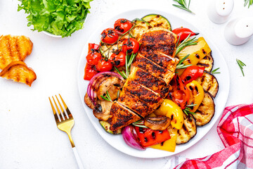 BBQ lunch. Grilled chicken breast and various vegetables on plate, white background, top view