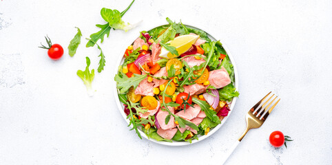 Fresh vegetable salad with canned tuna, tomatoes, onion, corn, paprika and arugula. White  background, top view